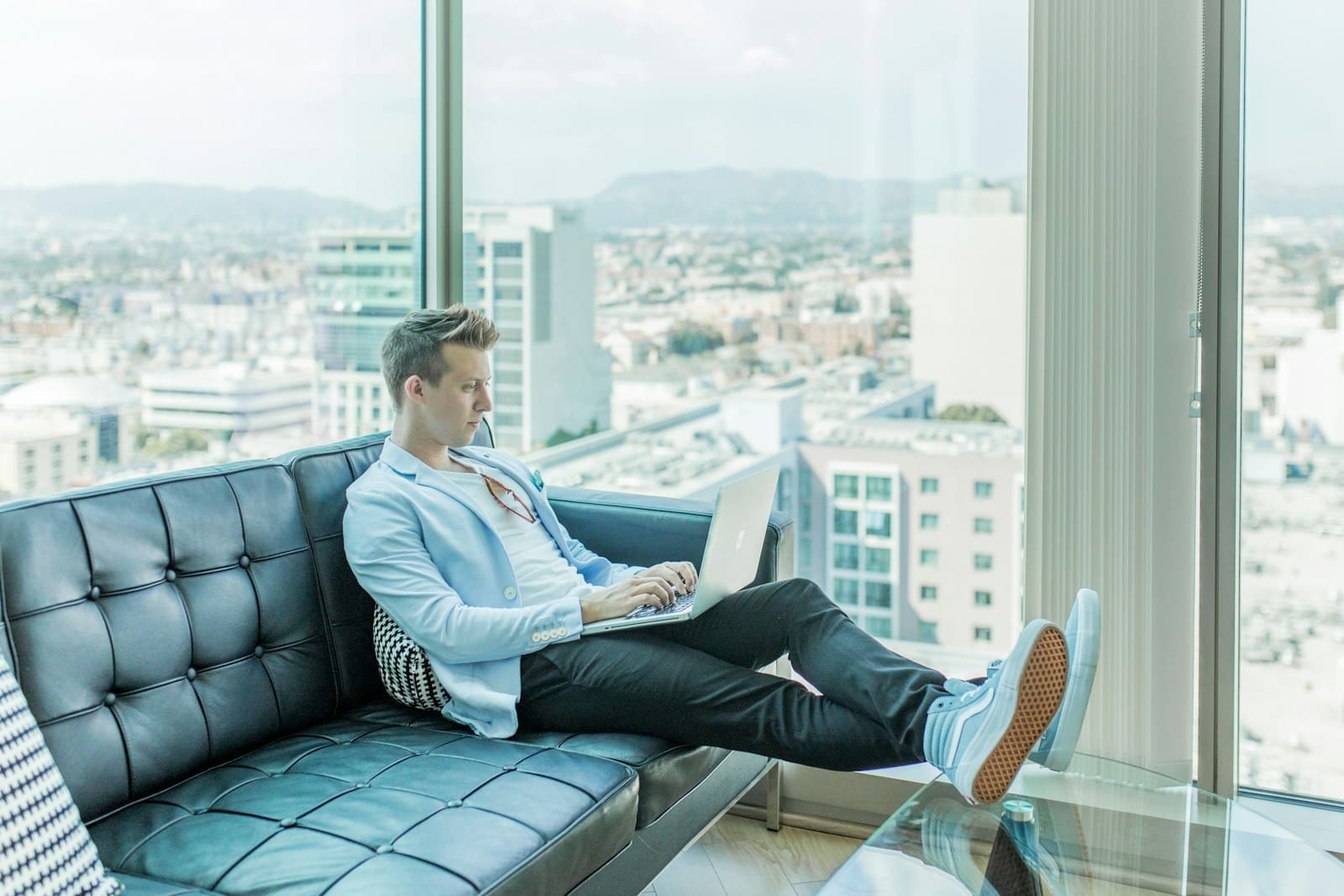Photo by Austin Distel man sitting on sofa while using laptop