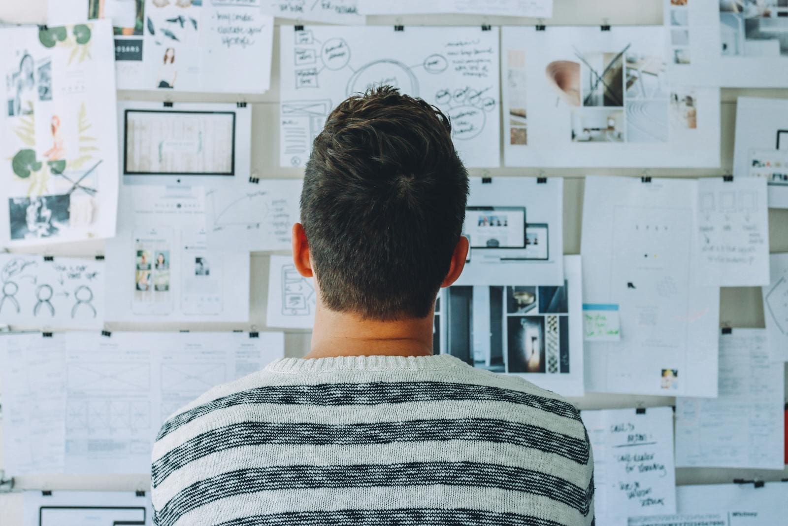 Photo by Startup Stock Photos Man Wearing Black and White Stripe Shirt Looking at White Printer Papers on the Wall